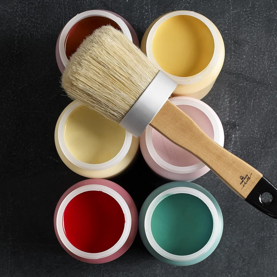 Open paint jars and a brush on a work surface
