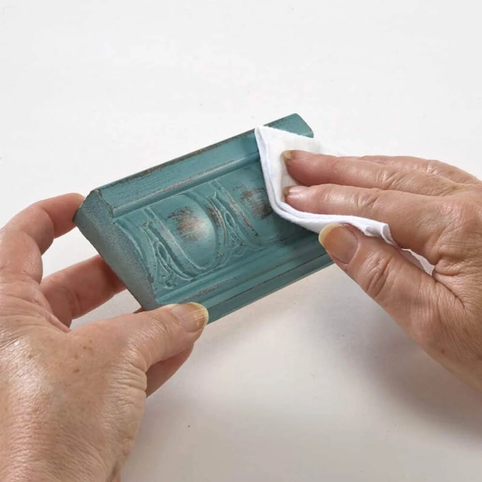 A soft cloth buffing a waxed decorative molding after the appropriate drying stage.